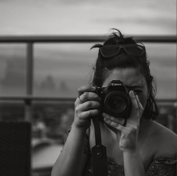 Photographer using a long lens camera to document an observation