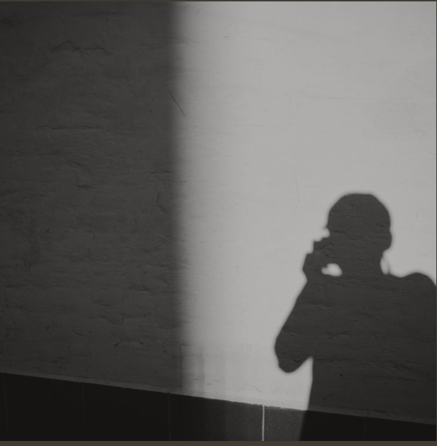 Shadow of a person on a phone cast against a plain wall