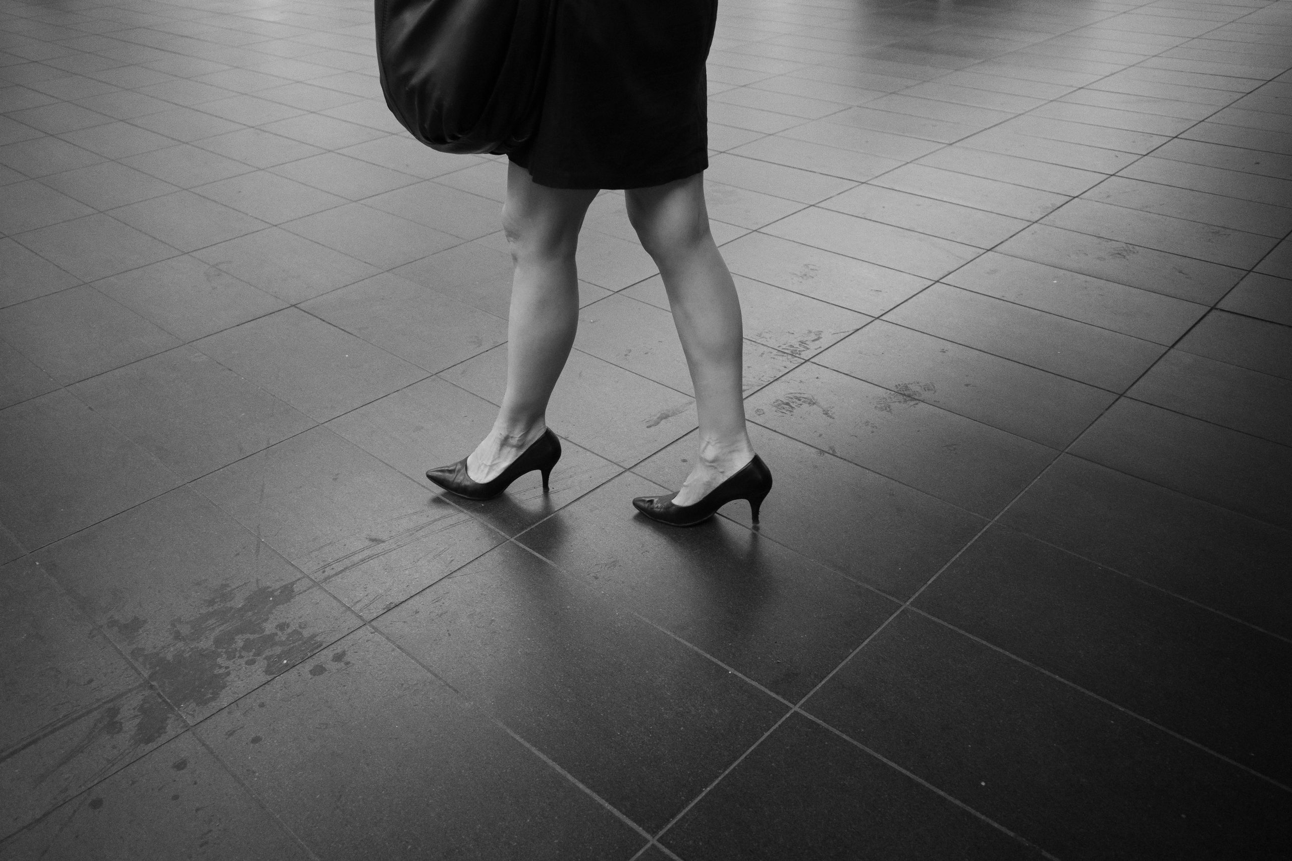 Person walking across a tiled floor, shown from the knees down